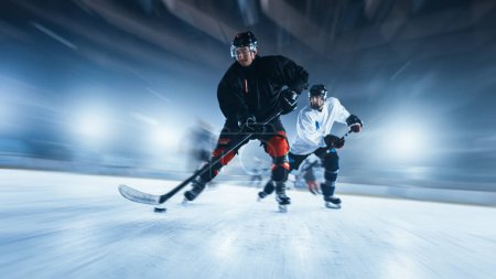 Foto de Ice Hockey Rink Arena: Jugador profesional delantero con maestría Dribbles, rompe la defensa y montar en cámara. Juego de equipos de rendimiento fuerte. Movimiento borroso Disparo. - Imagen libre de derechos