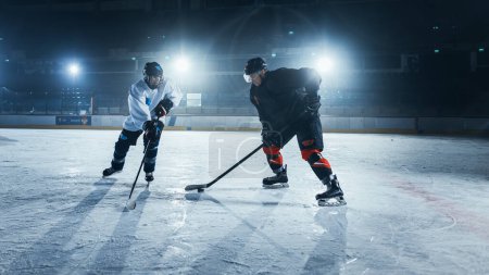 Foto de Arena de pista de hockey sobre hielo: Dos jugadores jóvenes entrenando, aprendiendo palillo y manejo de pato. Los atletas aprenden a driblar, atacar, defender, proteger, poseer, conducir el pato. - Imagen libre de derechos