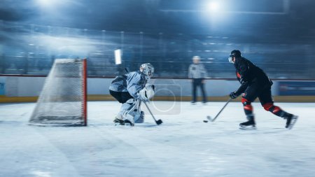 Photo for Ice Hockey Rink Arena: Goalie is Ready to Defend Score against Forward Player who Shoots Puck with Stick. Forwarder against Goaltender One on One. Tension Moment with Blurred Motion. - Royalty Free Image