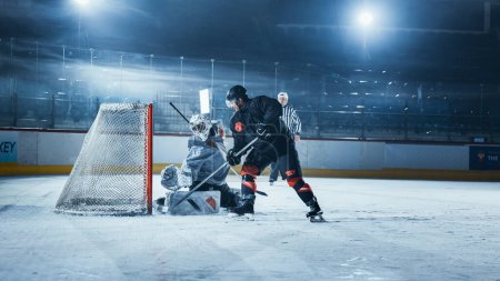 Photo for Ice Hockey Rink Arena: Goalie is Ready to Defend Score against Forward Player who Shoots Puck with Stick. Forwarder against Goaltender One on One. Tension Moment in Sport Full of Emotions. - Royalty Free Image