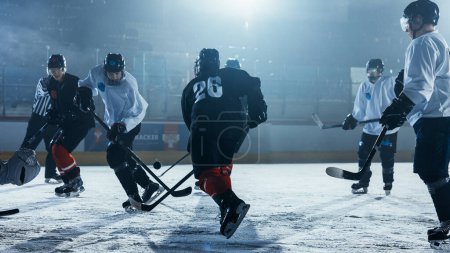 Téléchargez les photos : Patinoire de hockey sur glace Arena : Joueur avant professionnel brise la défense, frapper Puck avec bâton pour marquer un but. Deux équipes compétitives jouent. - en image libre de droit