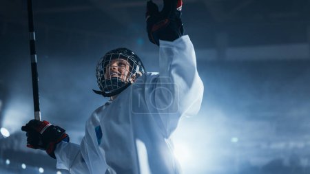 Eishockey-Profi feiert Sieg und hebt die Arme.