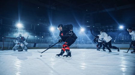 Foto de Ice Hockey Rink: Jugador profesional delantero rompe la defensa, Preparar para disparar Puck con palo para anotar gol. Dos equipos competitivos juegan juego intenso. - Imagen libre de derechos