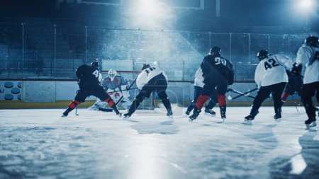 Foto de Ice Hockey Rink: Jugador profesional delantero rompe la defensa, Preparar para disparar Puck con palo para anotar gol. Dos equipos competitivos juegan juego intenso. - Imagen libre de derechos