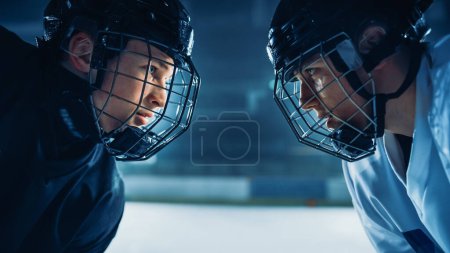Téléchargez les photos : Début du jeu de patinoire de hockey sur glace : deux joueurs professionnels face à face agressive, bâtons prêts. Intense jeu compétitif large d'énergie brute, vitesse, puissance, professionnalisme. Plan rapproché Portrait Shot - en image libre de droit