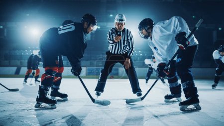 Téléchargez les photos : Début du match de l'aréna patinoire de hockey sur glace : deux joueurs brutaux affrontent, bâtons prêts, arbitre va lâcher le coup, athlètes prêts à se battre. Intense jeu large de la concurrence énergétique, la vitesse. - en image libre de droit