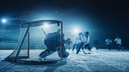 Foto de Ice Hockey Rink Arena: Goalie contra Forward Player que hace Slapshot, Shots Puck con Stick y anota gol. Forwarder contra Goaltender. - Imagen libre de derechos