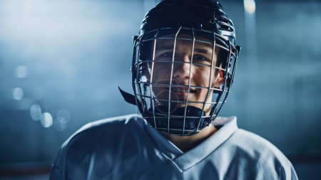 Foto de Arena de hockey sobre hielo: Retrato de jugador profesional confiable, usando máscara facial de jaula de alambre, mirando a la cámara y sonriendo. Primer plano Shot - Imagen libre de derechos