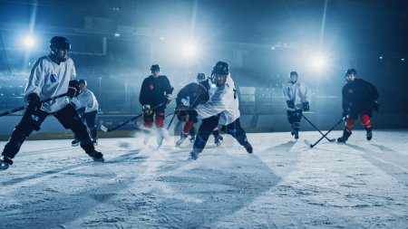 Foto de Ice Hockey Rink Arena: Pase exitoso para el jugador delantero que hace Slapshot, tiros Puck con palo y anota un gol con un golpe de gran potencia. Cinematic Wide Shot - Imagen libre de derechos
