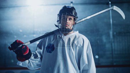 Foto de Ice Hockey Rink Arena: Retrato de jugador profesional de confianza, usando máscara facial de jaula de alambre, mirando a la cámara y sonriendo. Atleta enfocado, decidido a ganar y convertirse en campeón. - Imagen libre de derechos