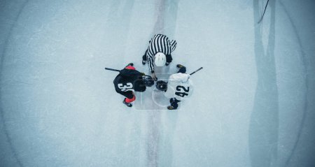 Top View Ice Hockey Rink Arena Game Start: Two Players Face off, Sticks Ready, Referee Ready to Drop the Puck. Intense Game Wide of Competition. Aerial Shot