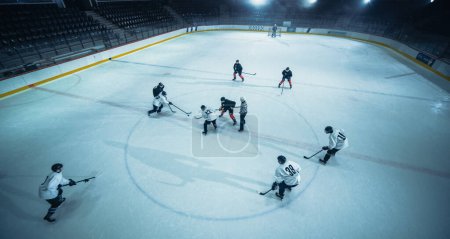 Aerial Ice Hockey Rink Arena Game Start: Two Players Brutal Face off, Referee Drops the Puck, Leading with Masterful Dribble Player Scores Goal when Goalie Misses the Puck. Drone High Angle Shot