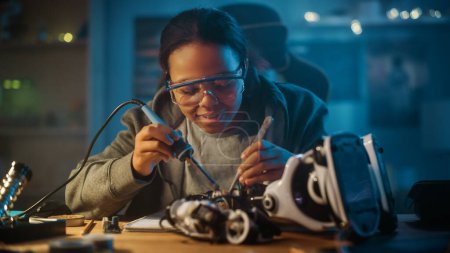 Photo for Young Teenage Multiethnic Schoolgirl is Studying Electronics and Soldering Wires and Circuit Boards in Her Science Hobby Robotics Project. Girl is Working on a Robot in Her Room. Education Concept. - Royalty Free Image