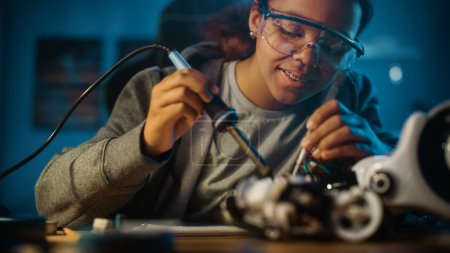 Photo for Young Teenage Multiethnic Schoolgirl is Studying Electronics and Soldering Wires and Circuit Boards in Her Science Hobby Robotics Project. Girl is Working on a Robot in Her Room. Education Concept. - Royalty Free Image