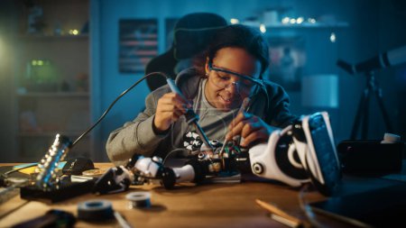 Foto de Young Teenage Multiethnic Schoolgirl está estudiando electrónica y soldadura de cables y placas de circuitos en su proyecto de robótica de ciencia Hobby. Chica está trabajando en un robot en su habitación. Concepto de educación. - Imagen libre de derechos