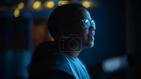 Photo for Portrait of a Teenage Multiethnic Black Girl Looking Out of the Window in Excitement. Surprised Young Female Watching the Night Sky from Her Home. She Wears Glasses and Dental Braces. - Royalty Free Image