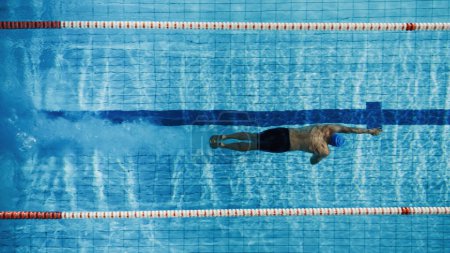 Téléchargez les photos : Nageur masculin mature musclé debout sur un bloc de départ et se préparant à sauter dans la piscine. Entraînement professionnel sain d'athlète pour le championnat. Tourné avec Sunflare - en image libre de droit