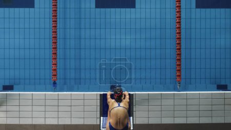 Foto de Muscular madura nadador masculino de pie en un bloque de partida y la preparación para saltar a la piscina. Entrenamiento de Atleta Profesional Saludable para el Campeonato. Disparo con Sunflare - Imagen libre de derechos