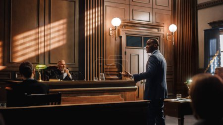 Photo for Court of Law, Trial in Session: Portrait of Charismatic Male Public Defender Making Touching, Passionate Speech to Judge and Jury. Attorney Lawyer Protecting Client, Presenting Case for Justice. - Royalty Free Image