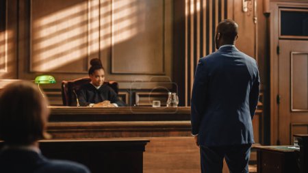 Photo for Court of Law and Justice Trial Proceedings: Male Law Offender is Questioned and Giving Testimony to Judge, Jury. Criminal Denying Charges, Pleading, Judge Accuses Guilty Defendant. - Royalty Free Image