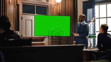 Photo for Court of Law Trial in Session: Portrait of Charismatic Male Public Defender Showing Evidence on Green Screen TV Display to Judge and Jury. Attorney Lawyer Protecting Client, Presenting Case. - Royalty Free Image