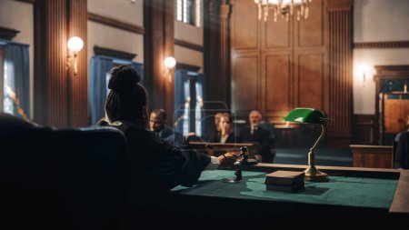 Photo for Cinematic Court of Law and Justice Trial: Female Judge Ruling Out a Decision in a Civil Family Case, Striking Gavel to Close Hearing. Convicted Male Defendant is Heartbroken, Lawyer Provides Support. - Royalty Free Image