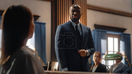 Court of Justice and Law Trial: Male Public Defender Presenting Case, Asking Female Witness in Front of Judge and Jury. African American Attorney Lawyer Protecting Client Against Crime, Injustice.