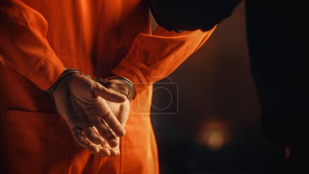 Filmreife Nahaufnahme eines in Handschellen gefesselten Verurteilten bei einem Gerichtsverfahren. Handschellen für den Angeklagten im orangefarbenen Gefängnisanzug. Gesetzesbrecher zu Gefängnisstrafe verurteilt.