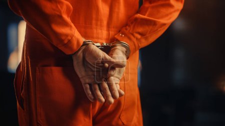 Filmreife Nahaufnahme eines in Handschellen gefesselten Verurteilten bei einem Gerichtsverfahren. Handschellen für den Angeklagten im orangefarbenen Gefängnisanzug. Gesetzesbrecher zu Gefängnisstrafe verurteilt.