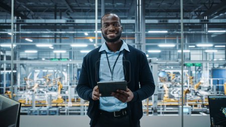 Photo for Car Factory Office: Portrait of Successful Black Male Chief Engineer Using Tablet Computer in Automated Robot Arm Assembly Line Manufacturing High-Tech Electric Vehicles. Medium Looking at Camera - Royalty Free Image