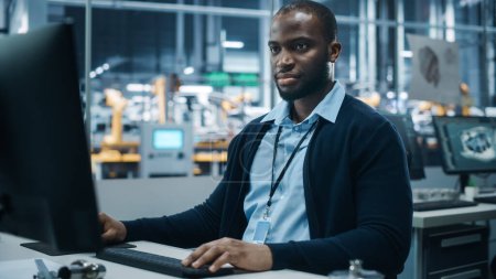 Photo for Car Factory Office: Portrait of Confident Black Male Chief Engineer Working on Desktop Computer. Professional Technician in Automated Robot Arm Assembly Line Manufacturing High-Tech Electric Vehicles - Royalty Free Image