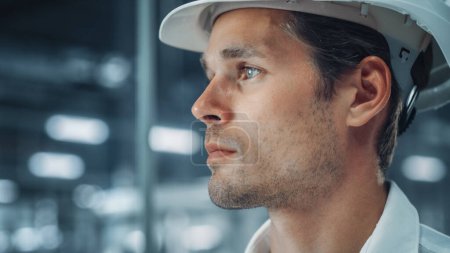 Photo for Portrait of a Young Handsome Confident Engineer Wearing White Hard Hat in Office at Car Assembly Plant. Industrial Specialist Working on Vehicle Production in Modern Factory. Side Profile Face View. - Royalty Free Image