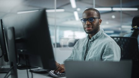 Photo for Authentic Office: Enthusiastic Black IT Programmer Starts Working on Desktop Computer. Male Website Developer, Software Engineer Developing App, Video Game. Terminal with Coding Programming Language - Royalty Free Image