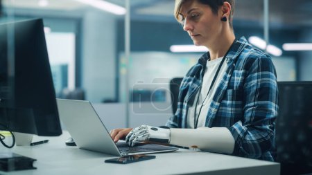 Diverse Body Positive Office: Portrait of Motivated Woman with Disability Using Prosthetic Arm to Work on Computer. Professional with Futuristic Thought Powered Myoelectric Bionic Hand