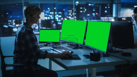 Photo for Night Office: Person with Disability Using Prosthetic Arm to Work on Green Screen Chroma Key Computer. Swift and Natural Use of Myoelectric Bionic Hand To Type Code for Software at Night. - Royalty Free Image