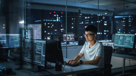 Night Office : Portrait d'un bel homme japonais travaillant sur ordinateur de bureau. Dactylographie numérique des entrepreneurs, création de logiciels modernes, conception d'applications de commerce électronique, programmation. Personne authentique élégante