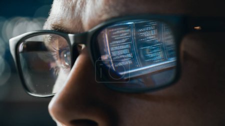 Téléchargez les photos : Décryptages Portrait d'ingénieur logiciel travaillant sur ordinateur, ligne de code réfléchissant dans les lunettes. Développeur Working on Innovative e-Commerce Application using Big Data Concept - en image libre de droit