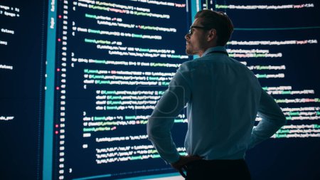 Photo for Innovative Startup Concept: Thoughtful Software Engineer Finding Solution, Planning Strategy, Standing and Doing Data Analysis on Big Wall Screen. Programmer Developing e-Commerce App. Back View Shot - Royalty Free Image