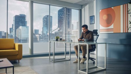 Téléchargez les photos : Portrait d'un homme d'affaires du Moyen-Orient assis à son bureau travaillant sur un ordinateur portable dans un grand bureau de la ville. Succès du Plan pour l'entrepreneuriat numérique Stratégie d'investissement pour le démarrage du commerce électronique. - en image libre de droit