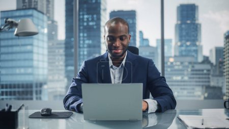 Téléchargez les photos : Portrait of Successful Black Businessman Working on Laptop Computer in His Big City Office. Professional Digital Entrepreneur effectue l'analyse de données pour l'évaluation de la stratégie de commerce électronique. - en image libre de droit