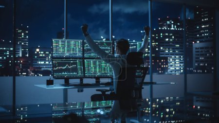 Stock Market Broker Working on a Computer with Multi-Monitor Workstation with Real-Time Investment, Commodities and Foreign Exchange Charts. Successful Businessman Punches Air for Winning a Trade.
