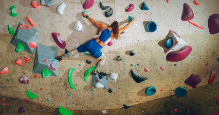Escalade Athlétique Féminine Pratiquant l'Escalade Solo sur le Mur de Bouldering dans une Salle de Gym. Femme faisant de l'exercice au centre de conditionnement physique intérieur, faisant du sport extrême pour son entraînement de mode de vie sain. Tourné de dos.