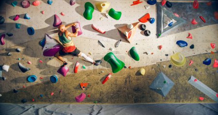 Photo for Strong Experienced Rock Climber Practicing Solo Climbing on Bouldering Wall in a Gym. Man Exercising at Indoor Fitness Facility, Doing Extreme Sport for His Healthy Lifestyle Training. Shot from Back. - Royalty Free Image