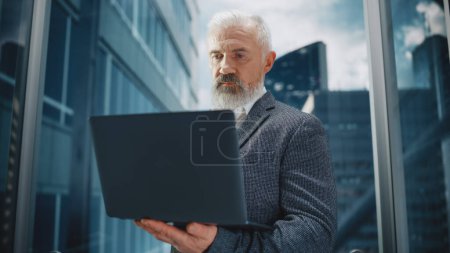 Photo for Successful Middle Aged Businessman Riding Glass Elevator to Office in Modern Business Center. Handsome Happy Man Using Laptop Computer, Check Schedule - Royalty Free Image