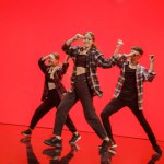 Diverse Group of Three Professional Dancers Performing a Hip Hop Dance Routine in Front of a Big Digital Led Wall Screen with Deep Orange and Red