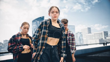 Foto de Diverso grupo de tres jóvenes bailarines profesionales que realizan una rutina de baile de Hip Hop en primer plano frente a una gran pantalla led con urbano moderno - Imagen libre de derechos