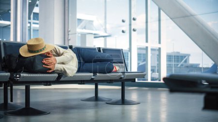 Foto de Terminal del aeropuerto: Hermosa mujer negra acostada para descansar y dormir mientras espera el vuelo de vacaciones. Joven y feliz viajando hembra duerme en - Imagen libre de derechos