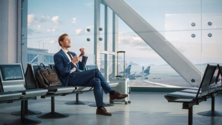 Photo for Airport Termina Flight Wait: Successful Businessman Uses Smartphone, Closes e-Business Deal and Celebrates Victory. Traveling Entrepreneur Remote Work - Royalty Free Image