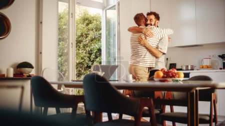 Téléchargez les photos : Des scènes douces d'un câlin élégant de couple gay jeune adulte à la maison. Deux hommes heureux amoureux qui s'amusent dans des vêtements décontractés dans le coin cuisine. Mignon LGBTQ - en image libre de droit