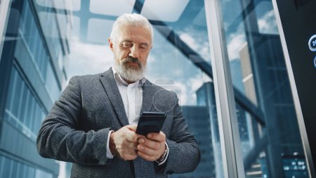 Photo for Successful Middle Aged Businessman Riding Glass Elevator to Office in Modern Business Center. Handsome Happy Man Using Smartphone, Write a Message - Royalty Free Image